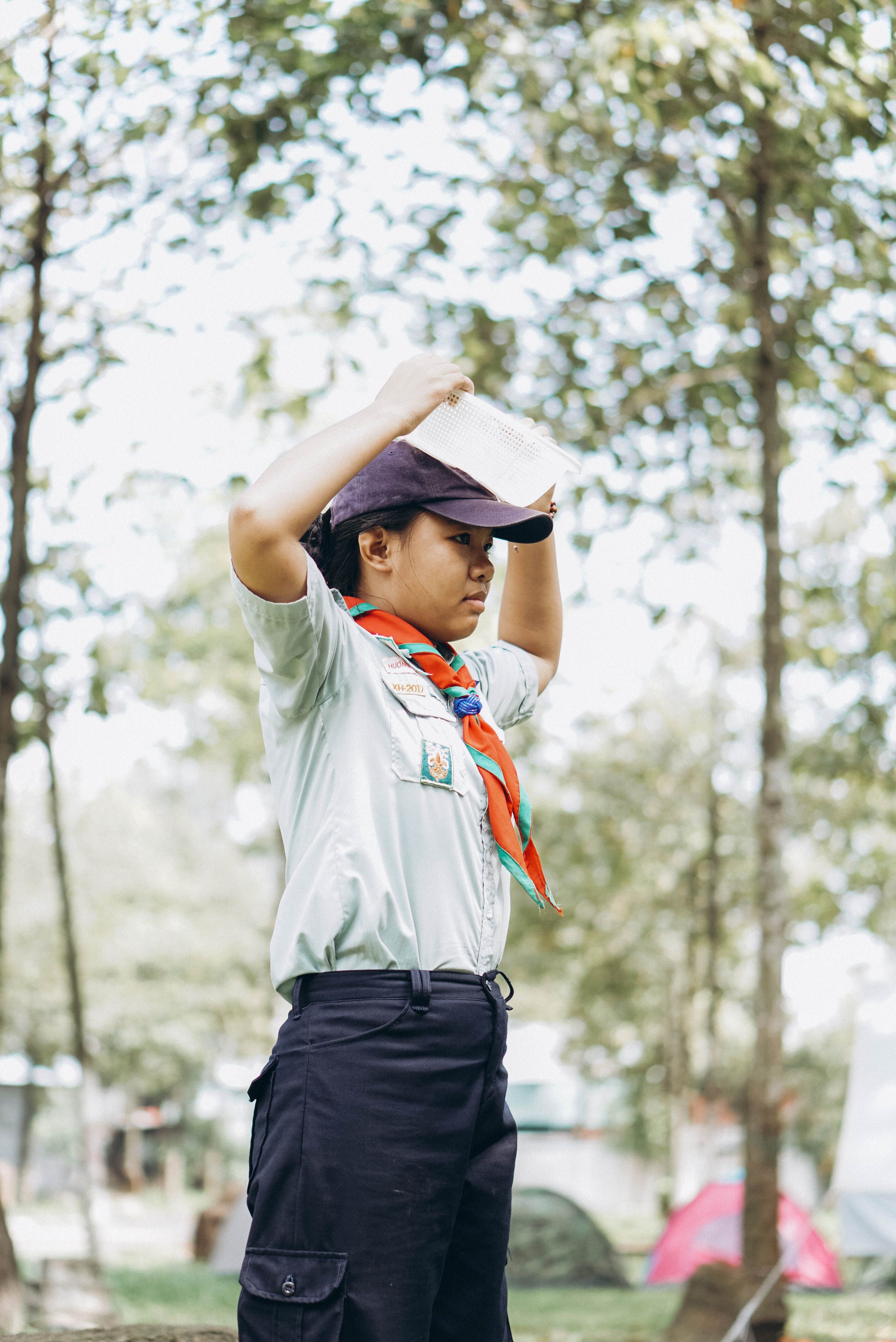 A young scout wearing a blue uniform and cap stands outdoors, ready for activities.