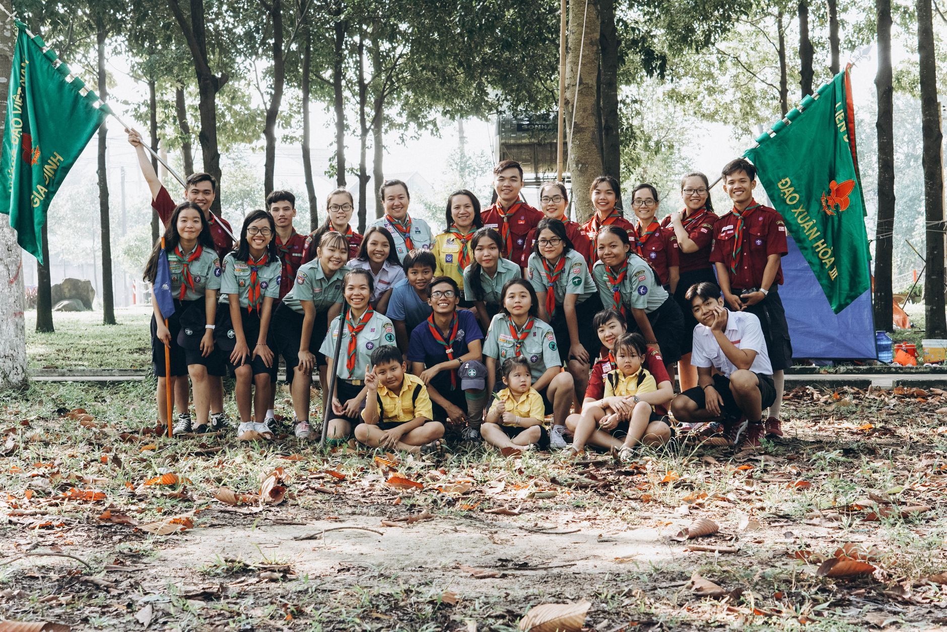 A cheerful group of scouts poses outdoors in a sunny forest, showcasing camaraderie and diversity.