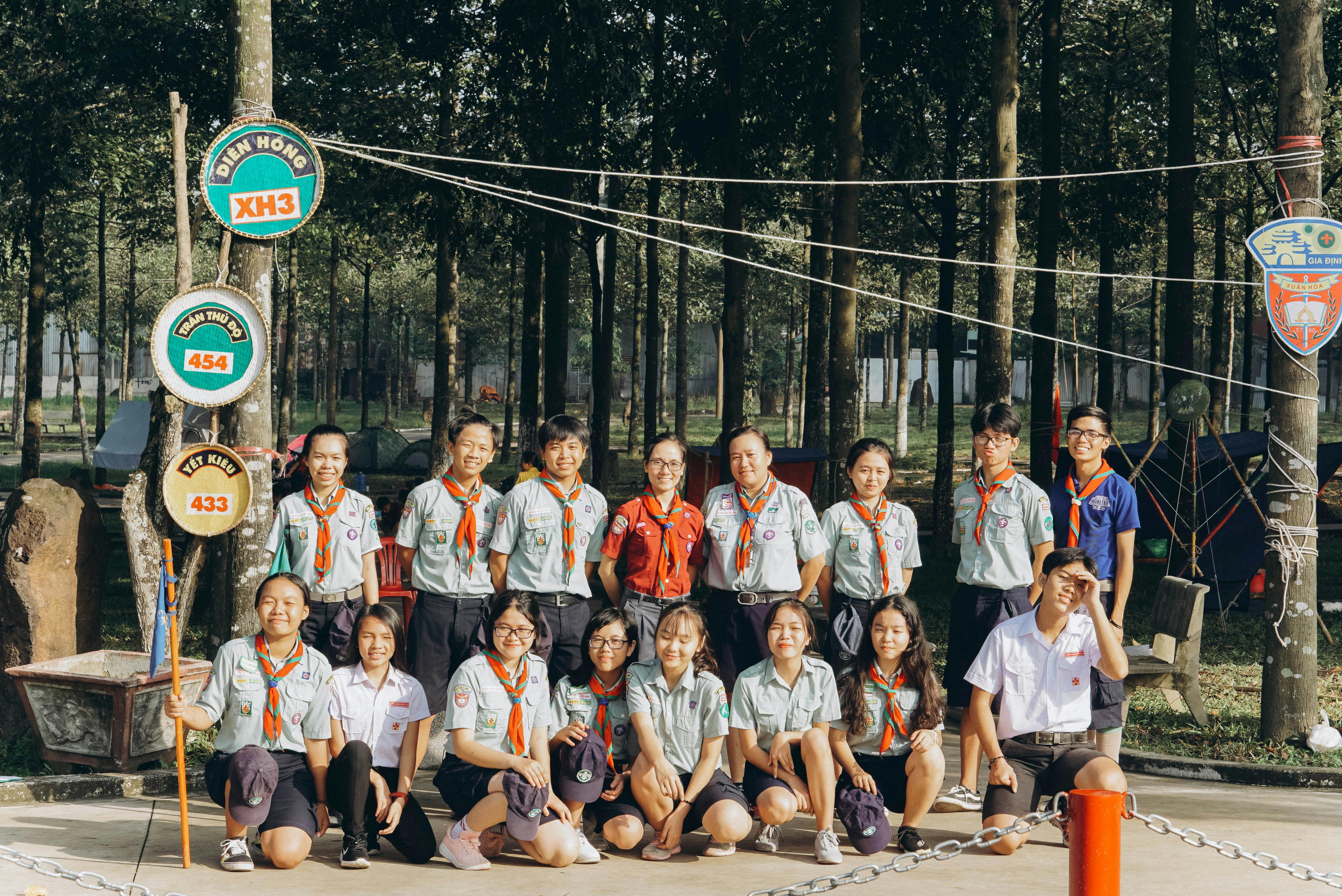 A group of scouts posing together in an outdoor forest setting, wearing uniform and smiles.