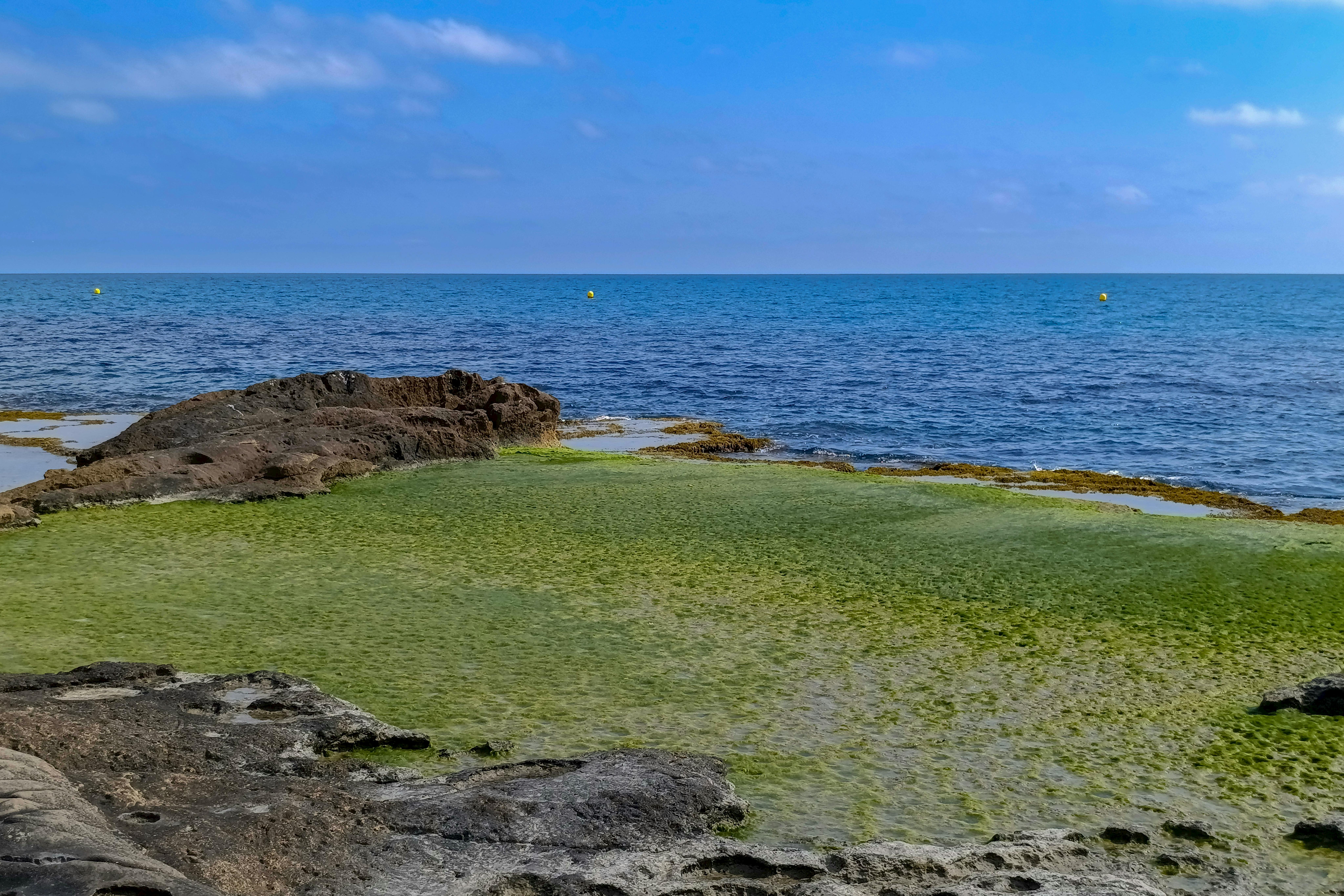 Beautiful coastal scene with rocky shoreline and clear blue water in Alicante, Spain.