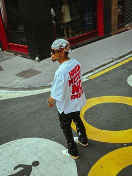 Young adult in stylish street fashion walking on colorful urban street.