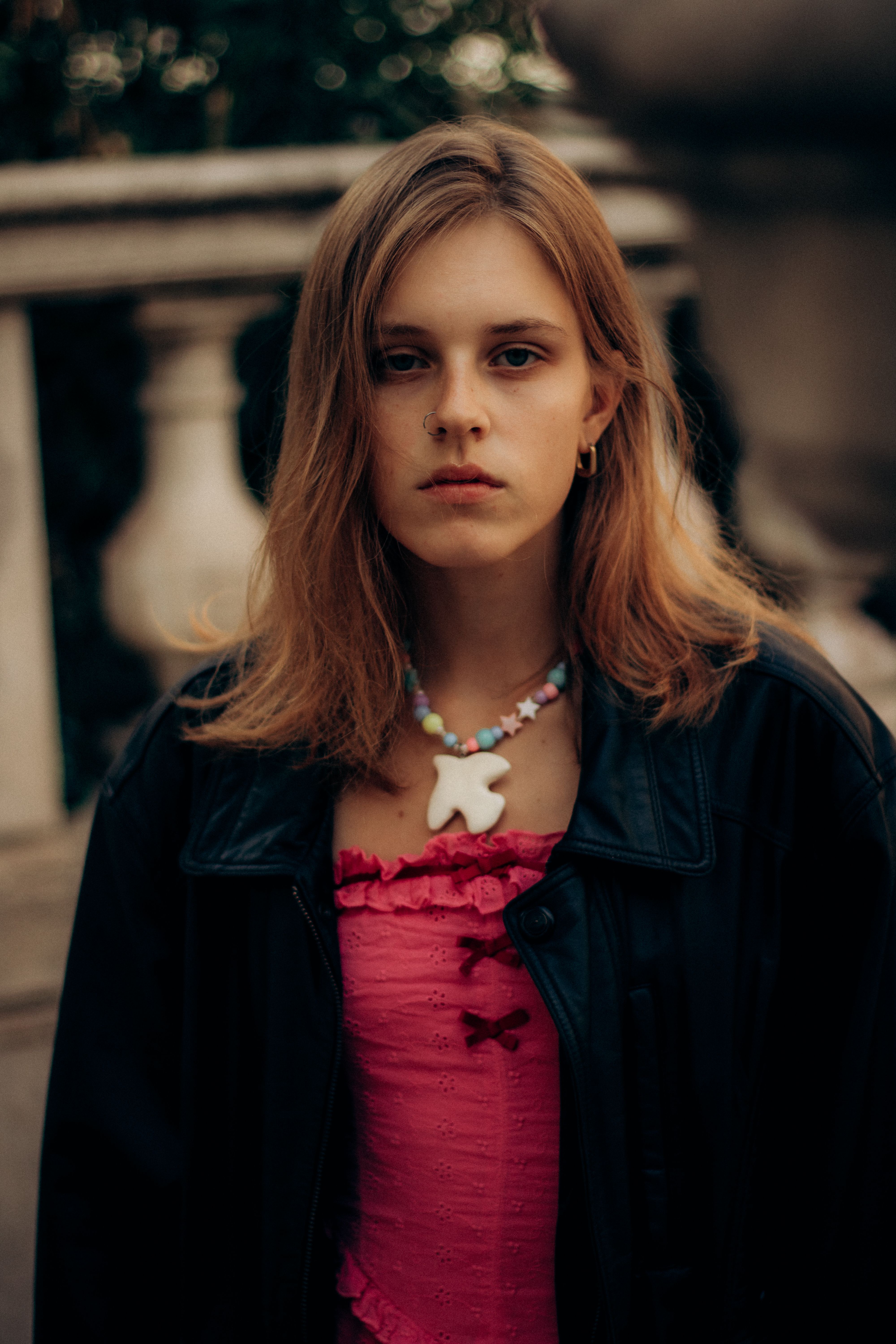 Portrait of a young woman in a pink top with a necklace outdoors in Marseille, France.