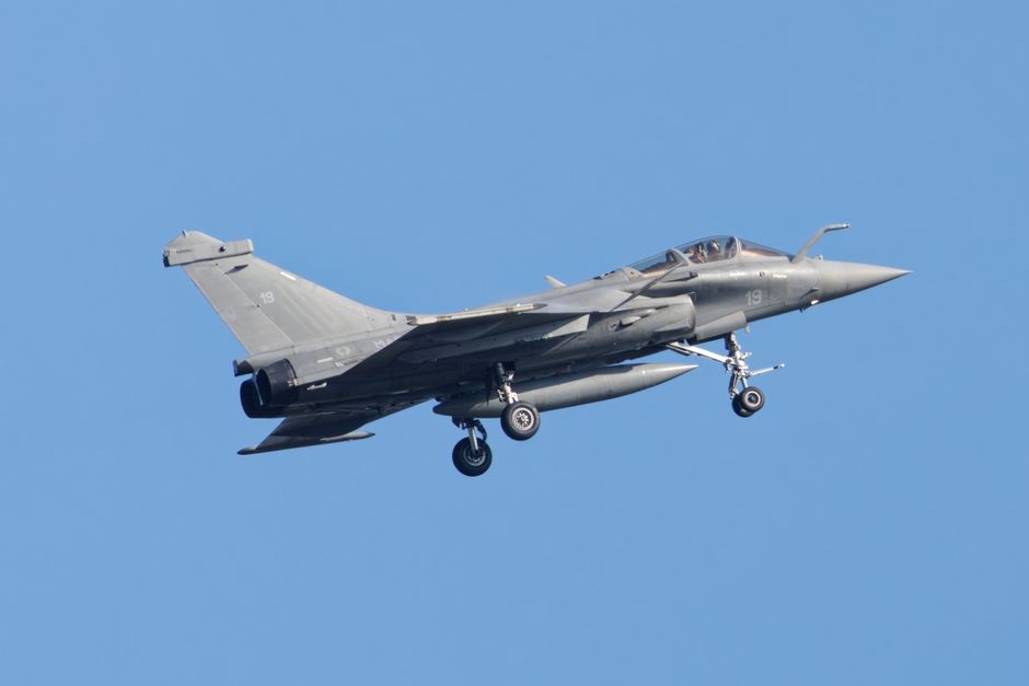 A sleek military jet flying high in the clear blue sky, showcasing aerodynamic design and power.