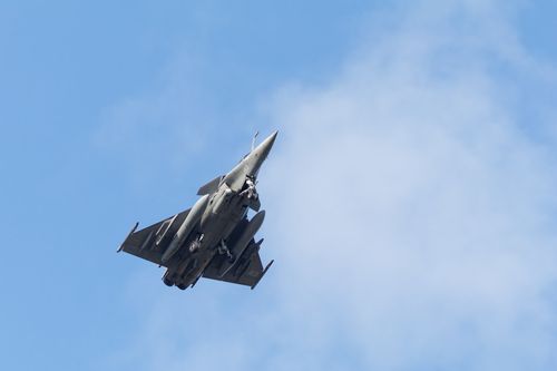 Free A sleek military jet fighter captured ascending against a bright blue sky. Stock Photo