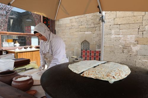 Free Woman prepares gözleme at a street food stall, showcasing traditional cooking methods. Stock Photo