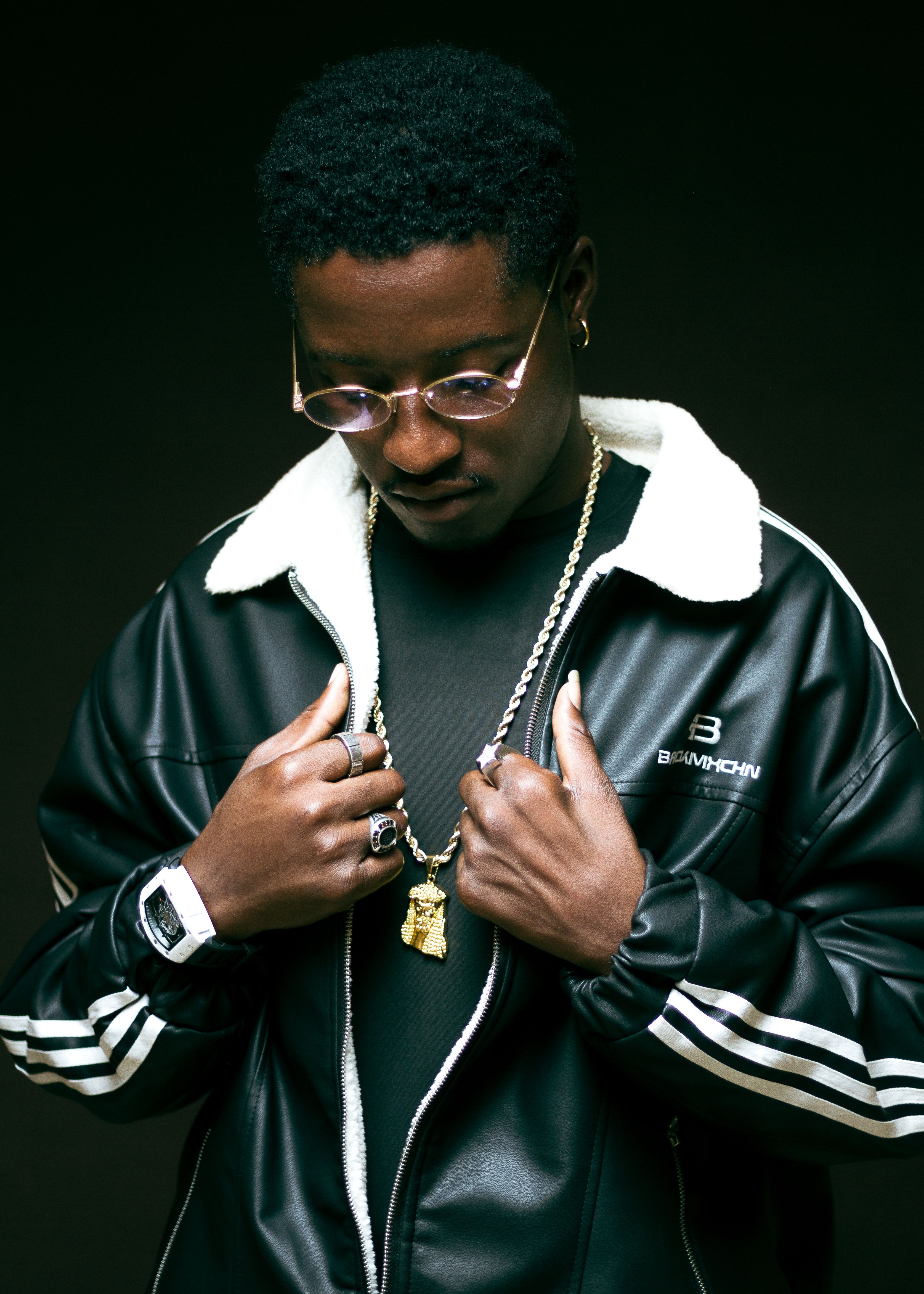 Portrait of a man wearing a black leather jacket and gold accessories, exuding urban style.