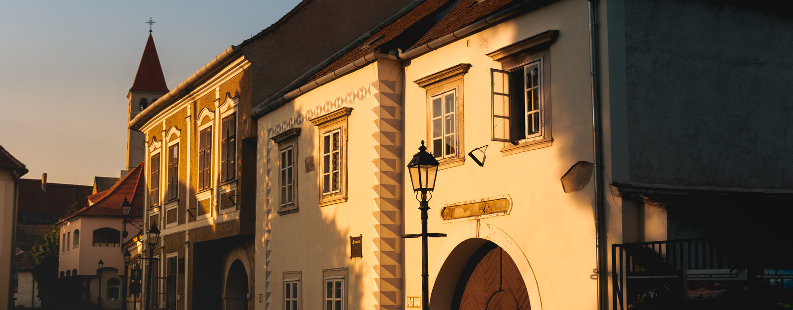 Historic buildings in Kőszeg, Hungary basking in golden sunset light, creating a warm and nostalgic atmosphere.