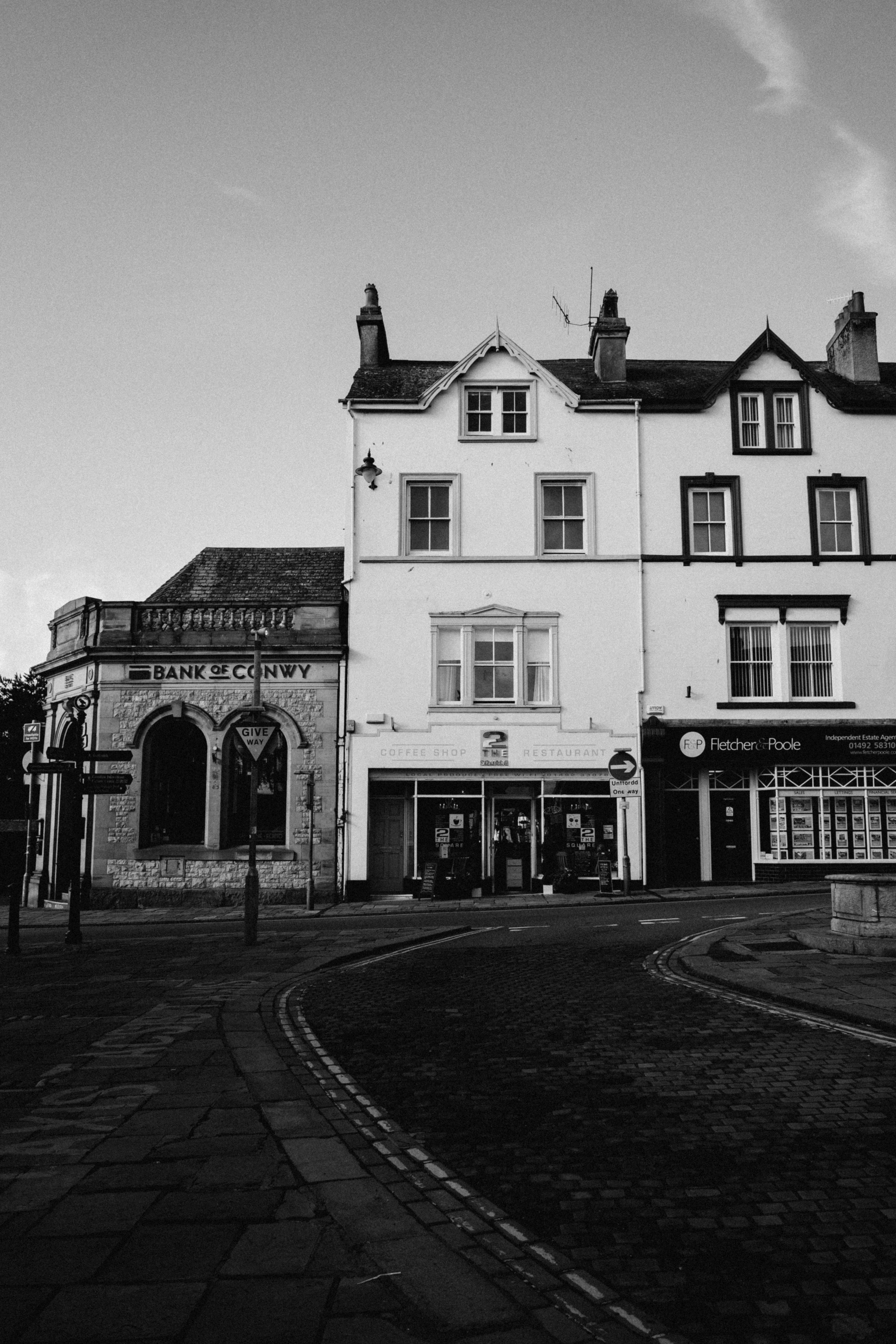 Black and white photograph of a street in Conwy, Wales featuring historic architecture.