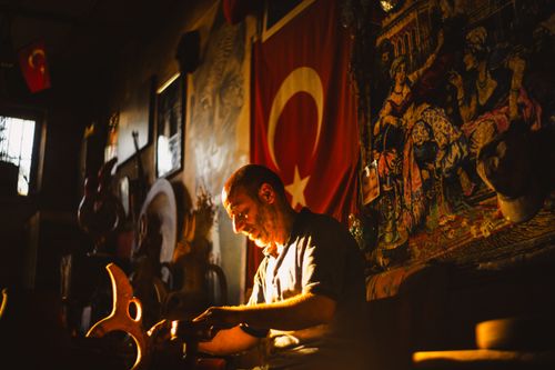 Free Skilled craftsman works under Turkish flag, highlighting traditional artistry. Stock Photo