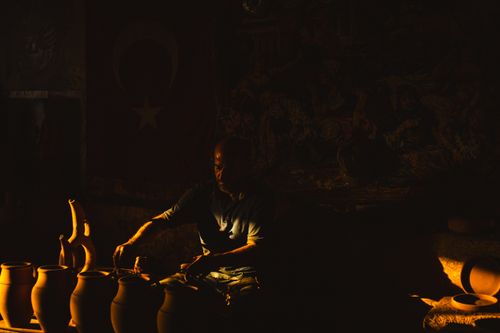 Free A Turkish artisan skillfully shaping clay pots, illuminated by warm light indoors. Stock Photo