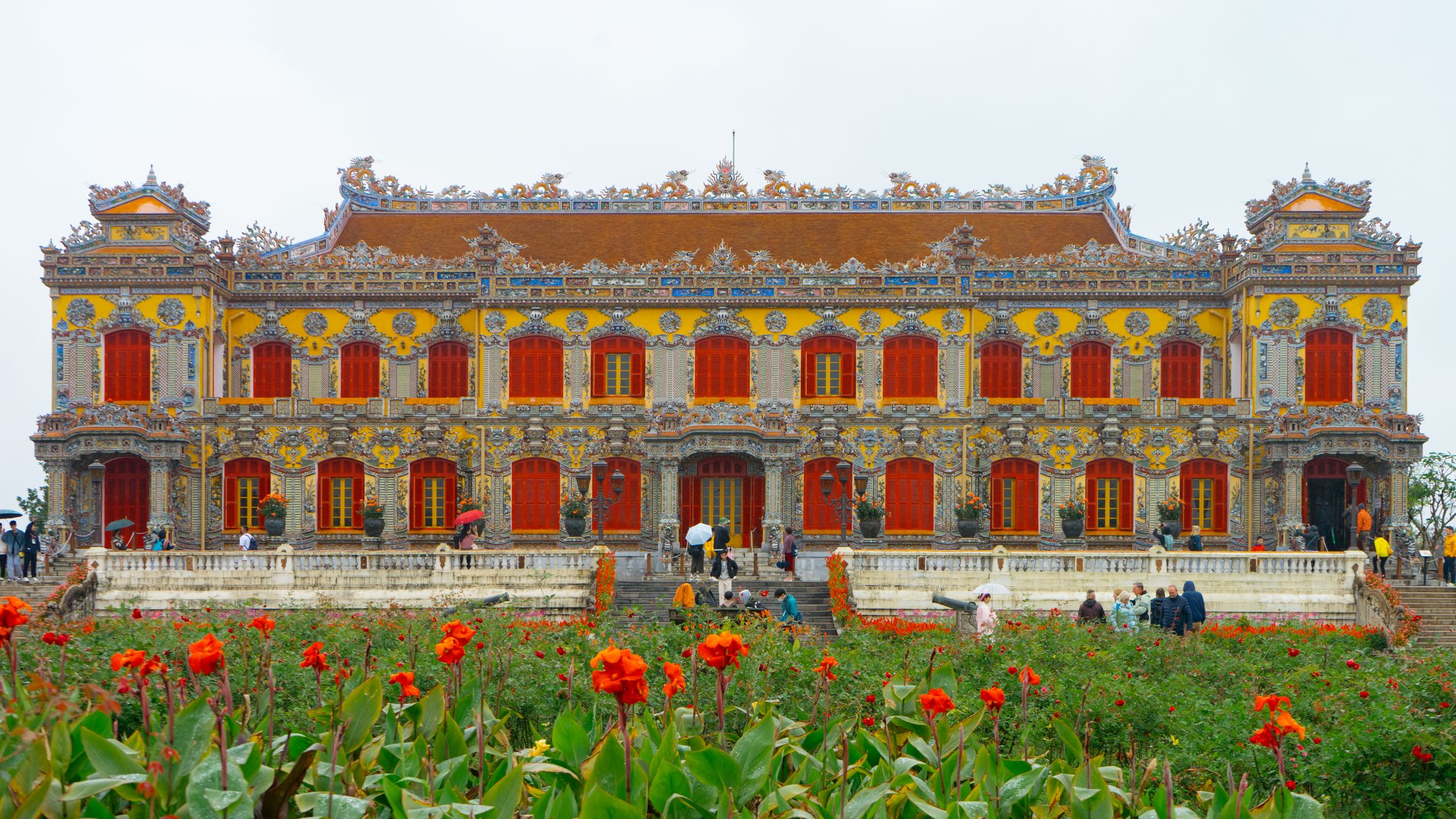 Vibrant entrance to the Imperial City in Hue, Vietnam, with colorful blooms in the foreground.