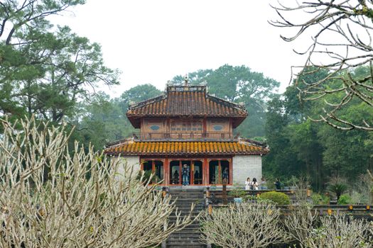 Explore the historic architecture of a traditional pagoda surrounded by lush greenery in Hue, Vietnam.