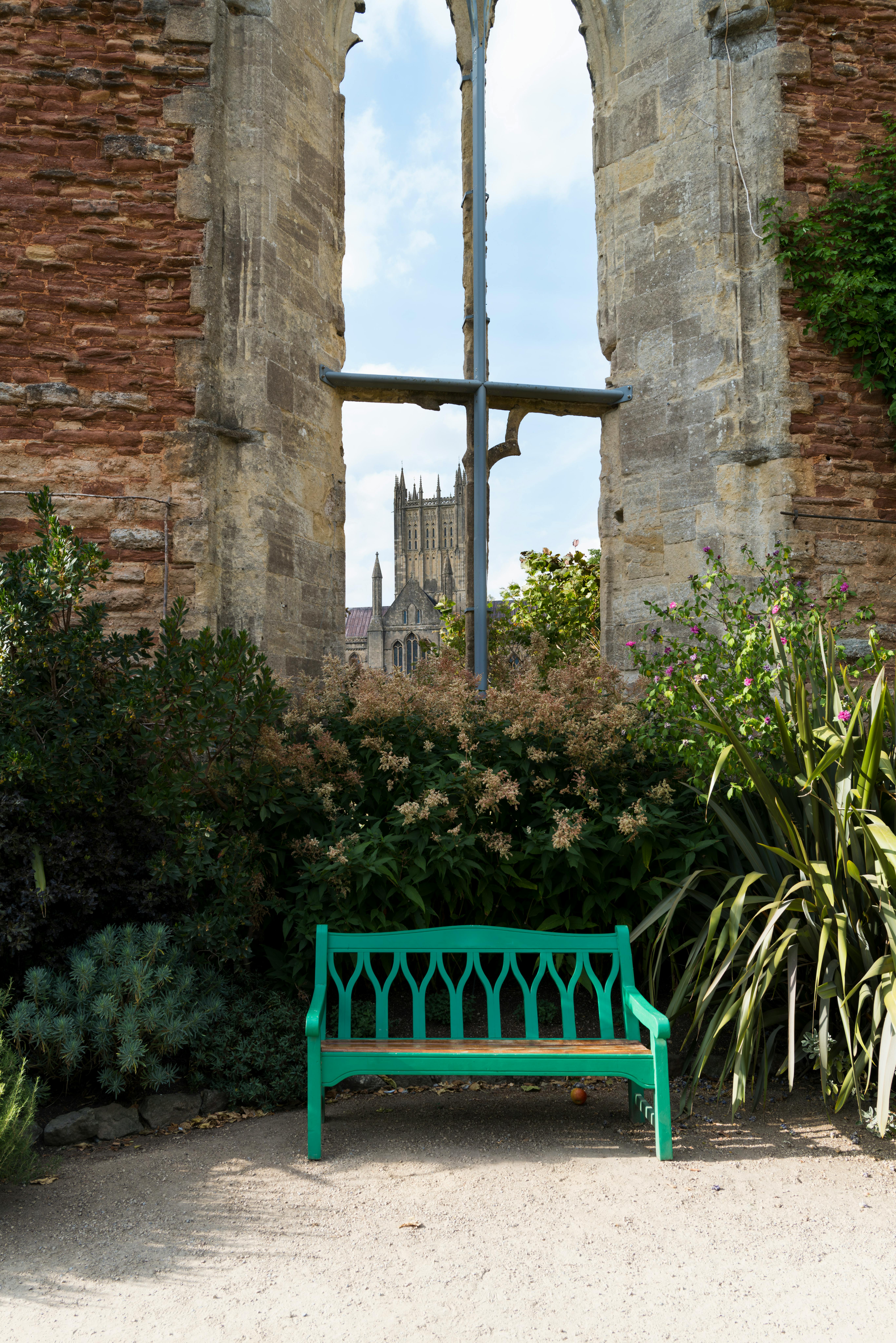 Tranquil garden scene with gothic ruins framing a distant cathedral in Wells, England.