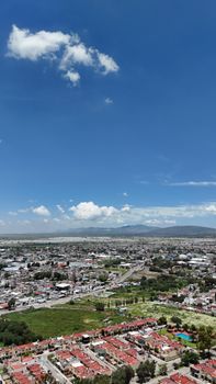 Stunning aerial view of a Mexican cityscape with vibrant rooftops under a clear blue sky, showcasing urban and natural landscapes.