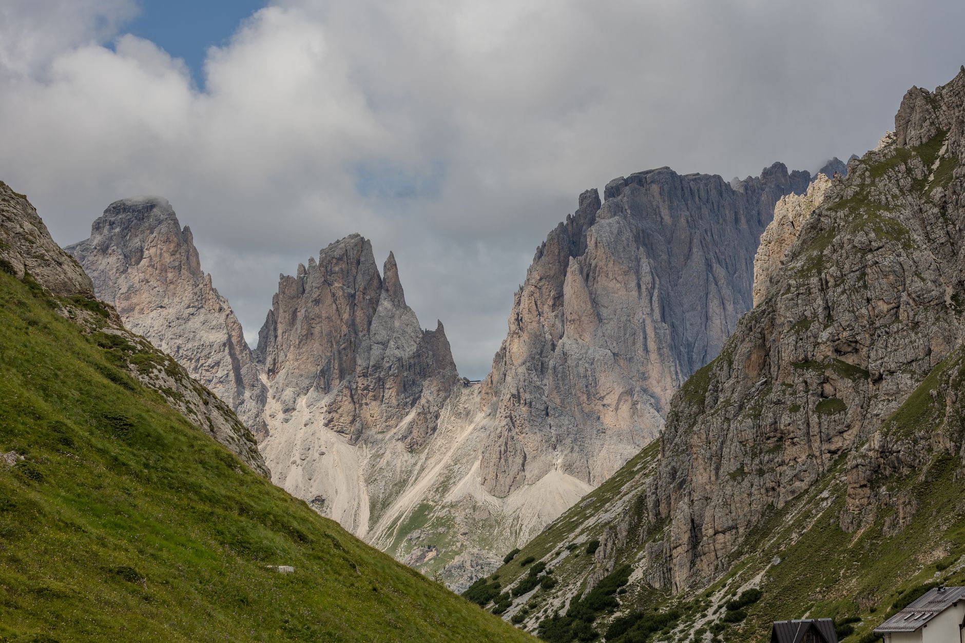 Stunning view of the Dolomites peaks surrounded by green valleys under a cloudy sky.