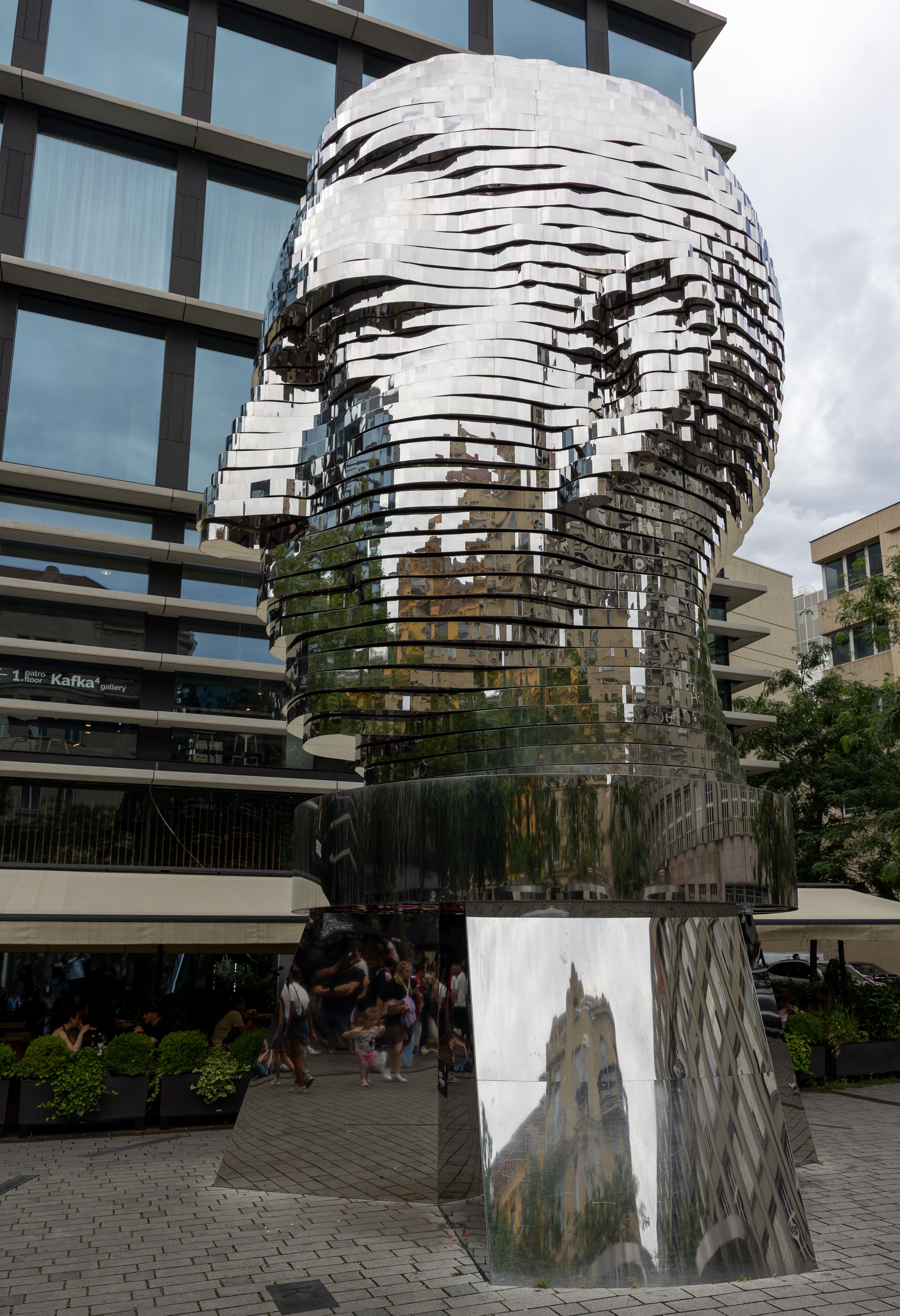 Reflective Kafka Head sculpture by David Cerny in Prague with visitors.