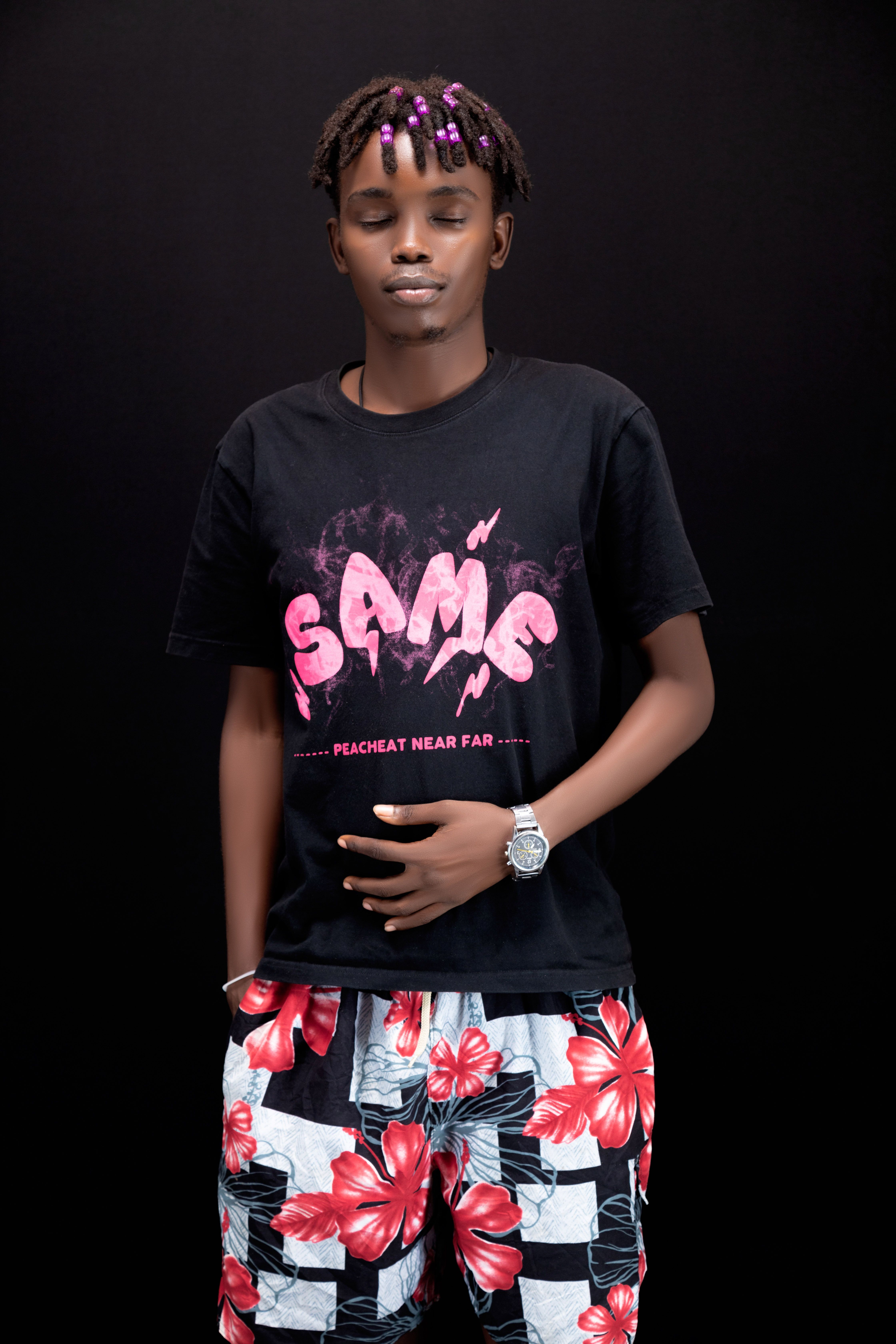 Portrait of a fashionable young man in casual attire with floral shorts and graphic tee.