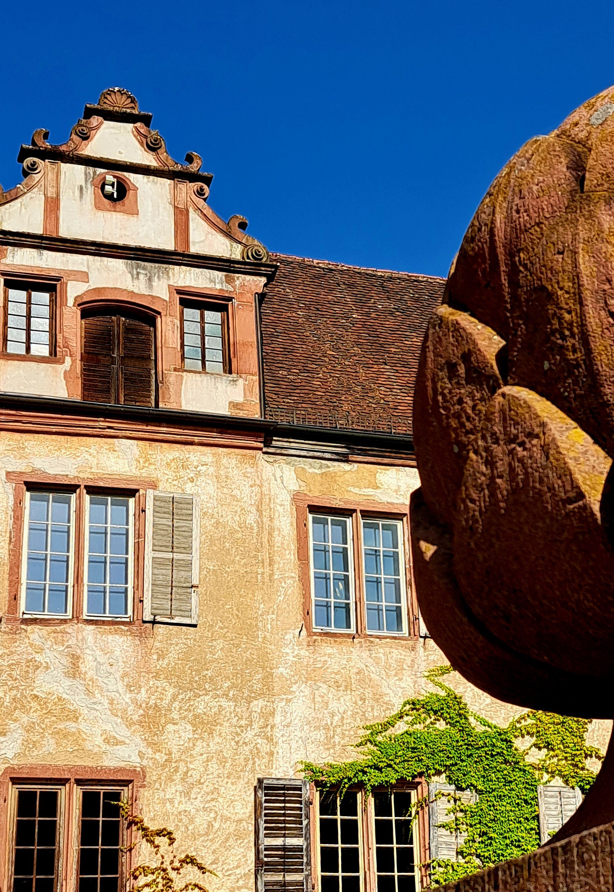 Charming facade of a historic European manor against a clear blue sky, showcasing architectural details.