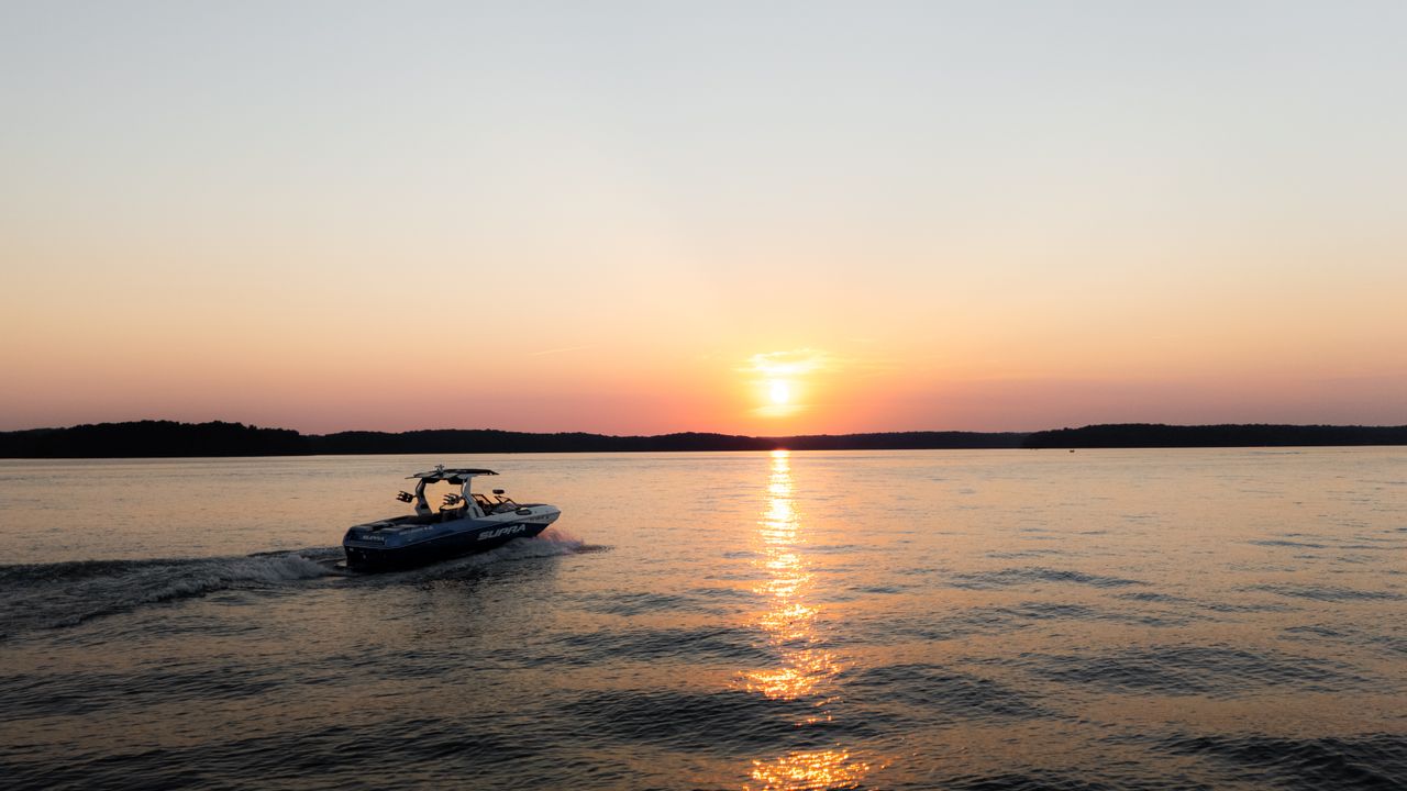 a speedboat navigates a serene lake as the sun sets casting colorful r