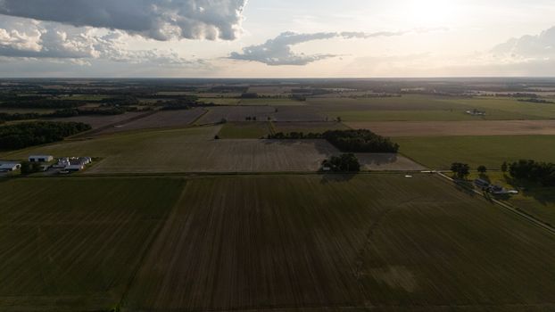 A vast aerial shot capturing agricultural fields and serene farm landscapes during a tranquil sunset.