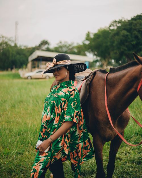 Free Stylish woman in green dress beside horse in scenic countryside. Stock Photo