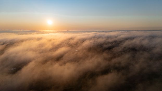Captivating aerial view of clouds illuminated by a warm sunset, creating a serene and dramatic scene.