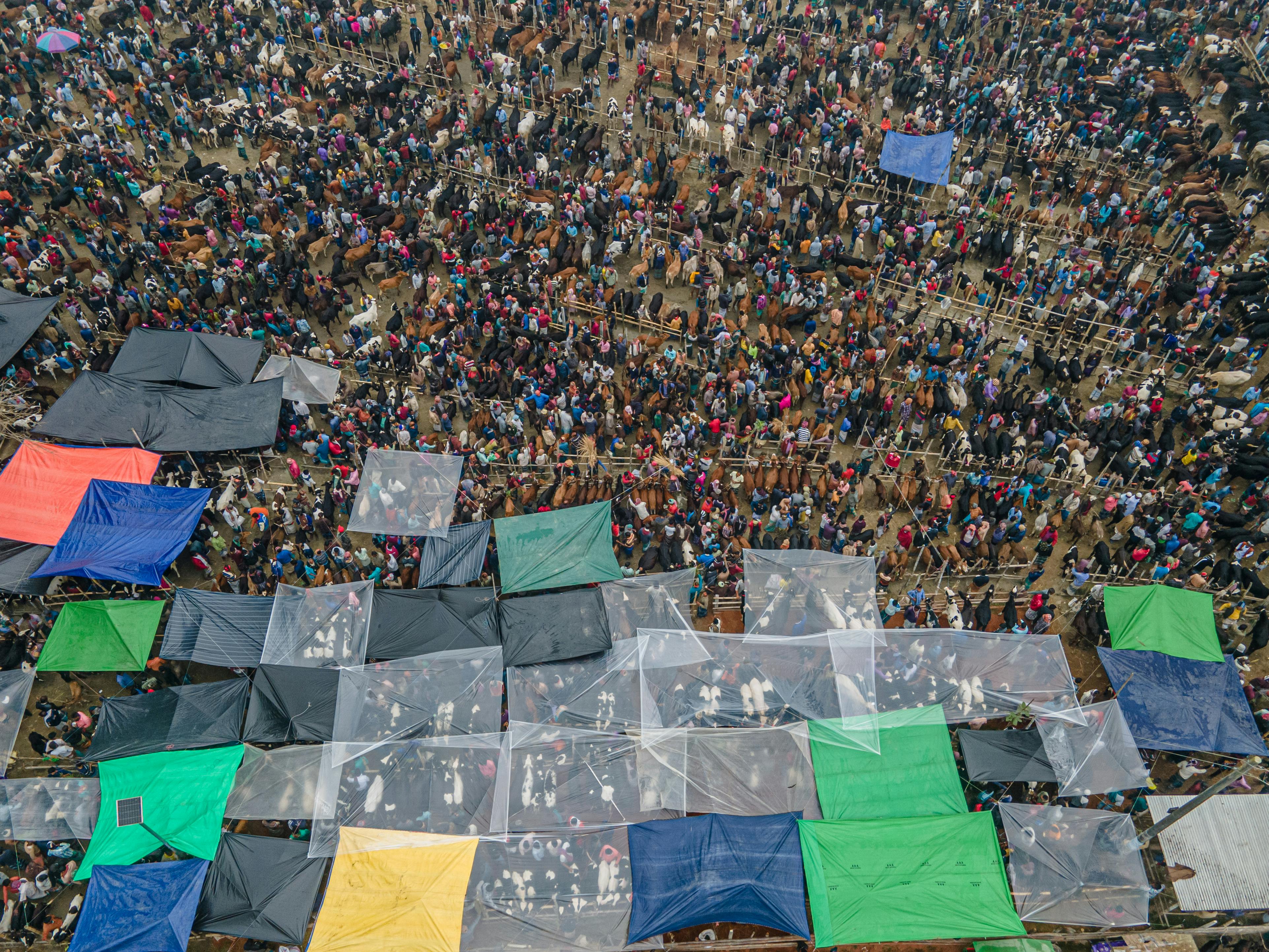 Vibrant aerial shot of a crowded outdoor market with colorful tents and people.