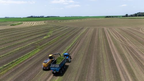 Free A tractor and harvester working in a vast, open farm field during harvest season. Stock Photo