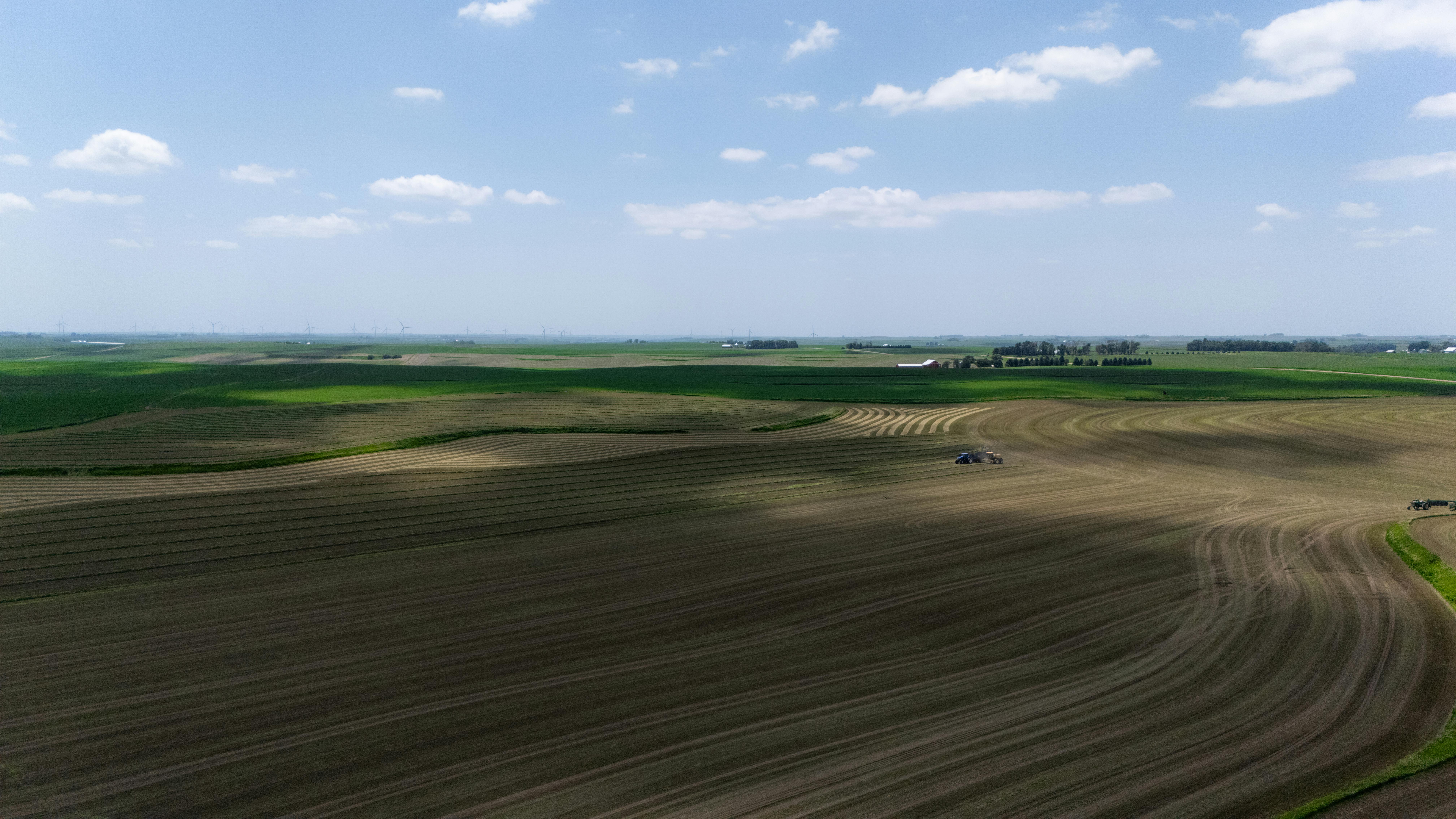 무료 여름 수확기 동안 트랙터가 있는 광활한 농장의 공중 사진입니다. 스톡 사진