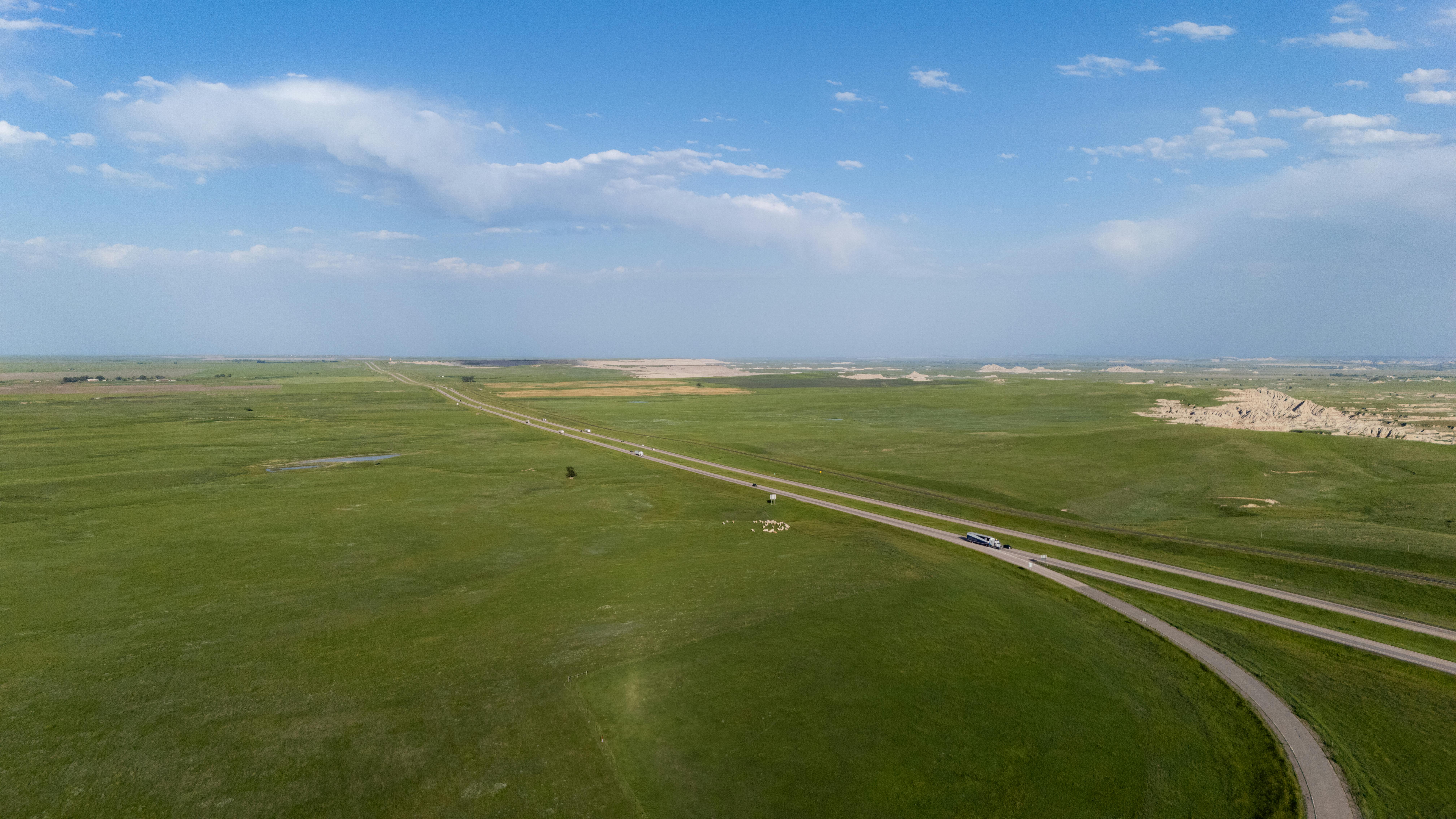 Breathtaking aerial view of vast grasslands spreading under a clear blue sky, highlighting natural beauty.