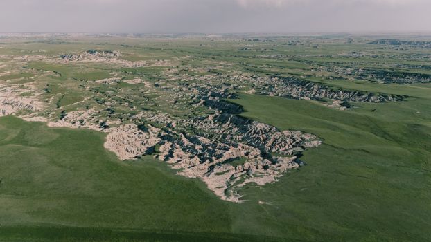 Stunning aerial shot showcasing expansive grasslands and intricate rock formations under a clear sky.