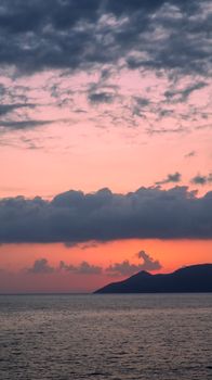 Breathtaking view of the sunset casting vibrant colors over the ocean and a silhouetted island.