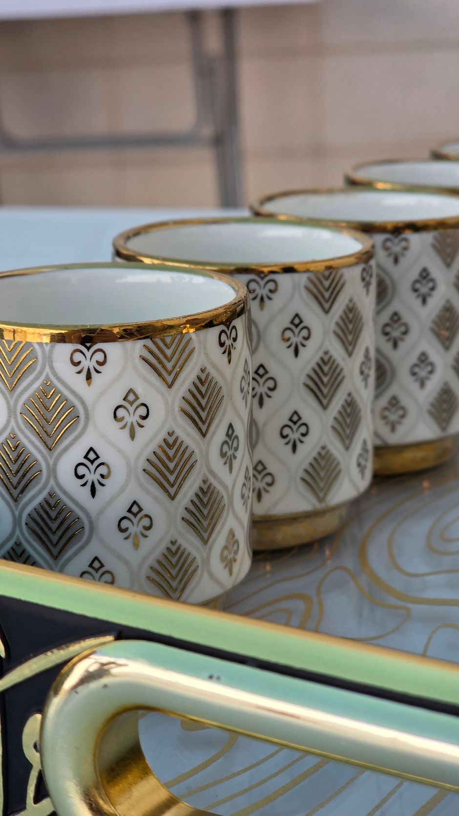 Stylish ceramic mugs with gold accents on a decorative tray.