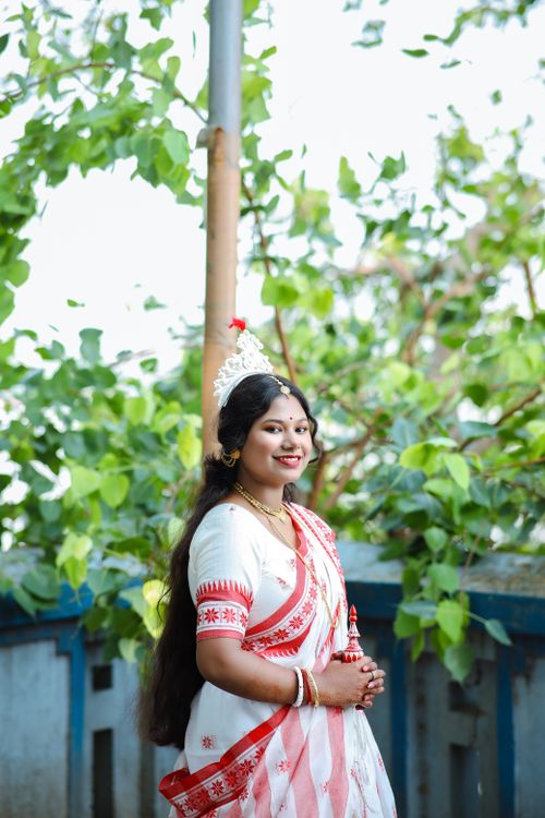 Free Smiling woman in vibrant traditional Assamese dress, outdoors with lush greenery. Stock Photo