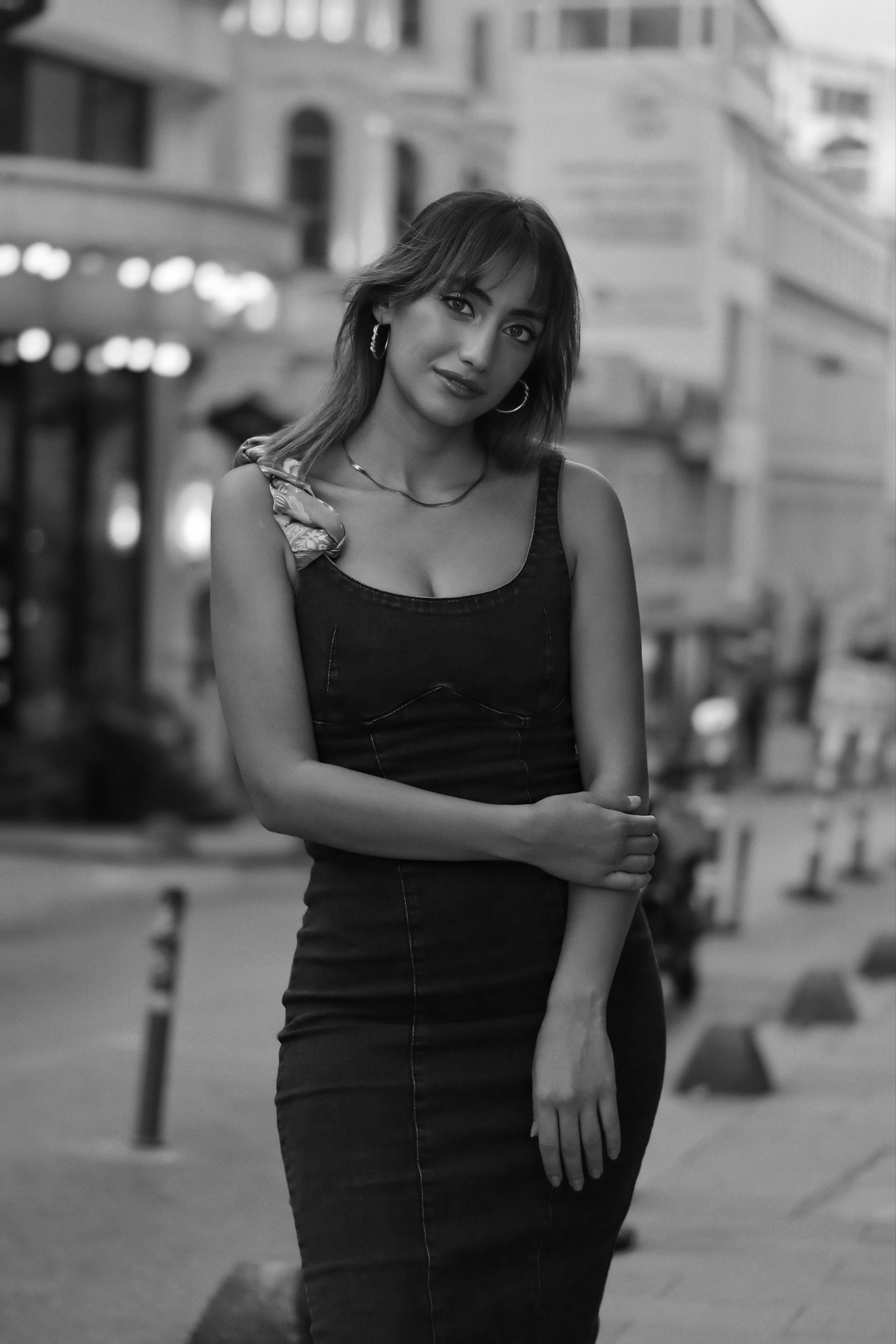 Elegant woman poses confidently on city street in a black dress, creating a timeless look.