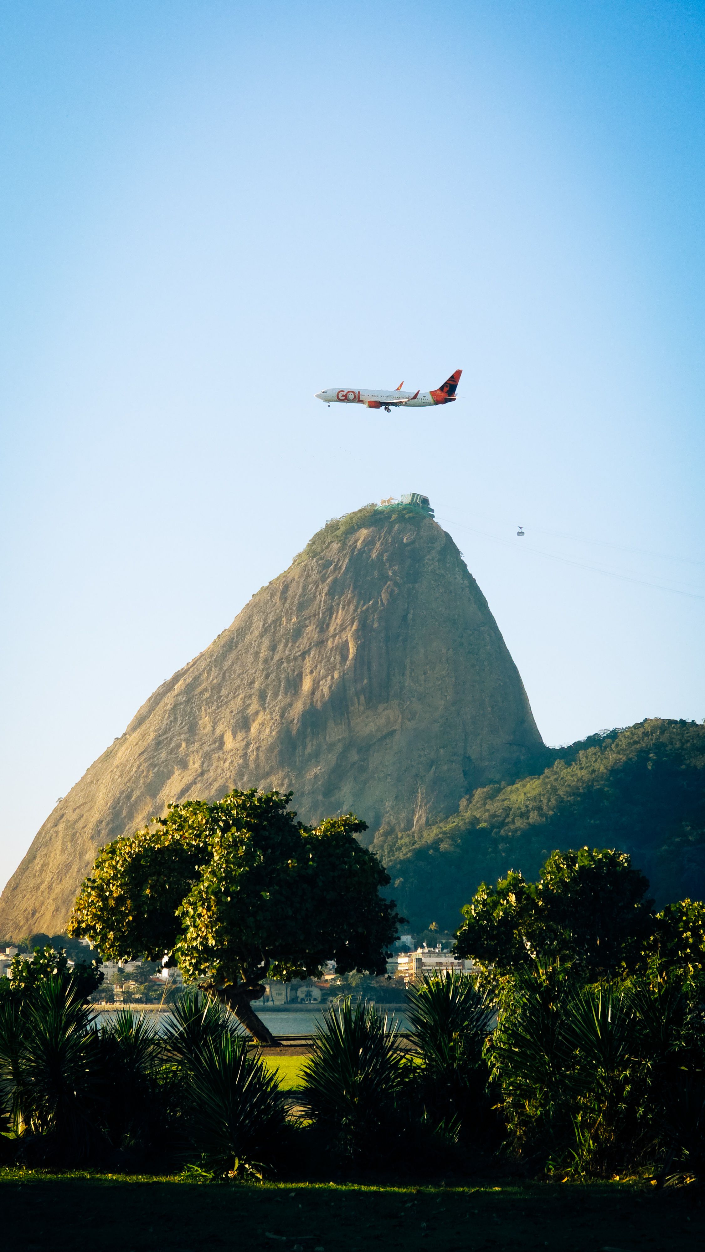 A scenic view of Sugarloaf Mountain with a plane flying above, captured on a sunny day.