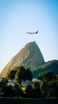A scenic view of Sugarloaf Mountain with a plane flying above, captured on a sunny day.