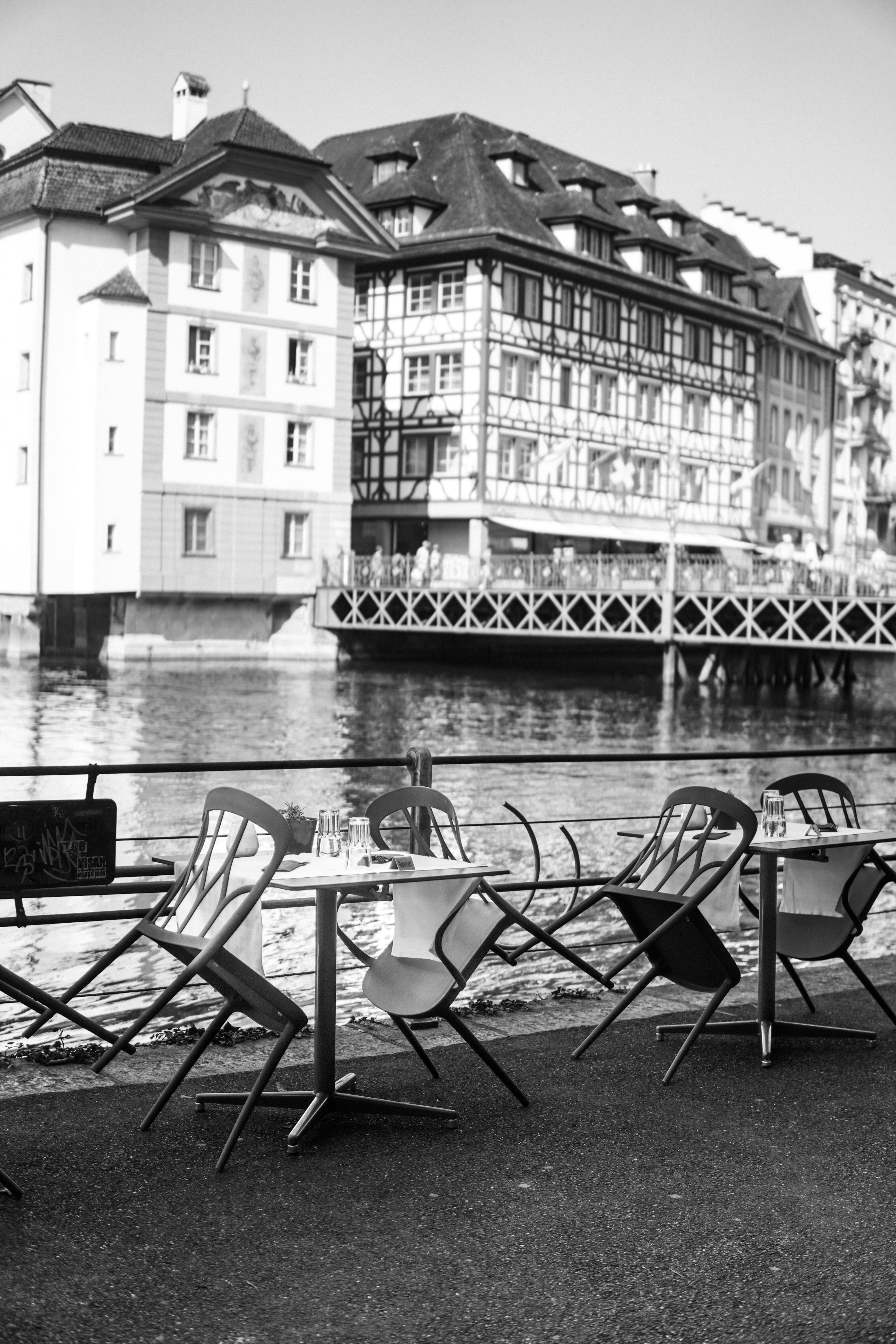 Black and white view of riverside cafe with historic buildings.