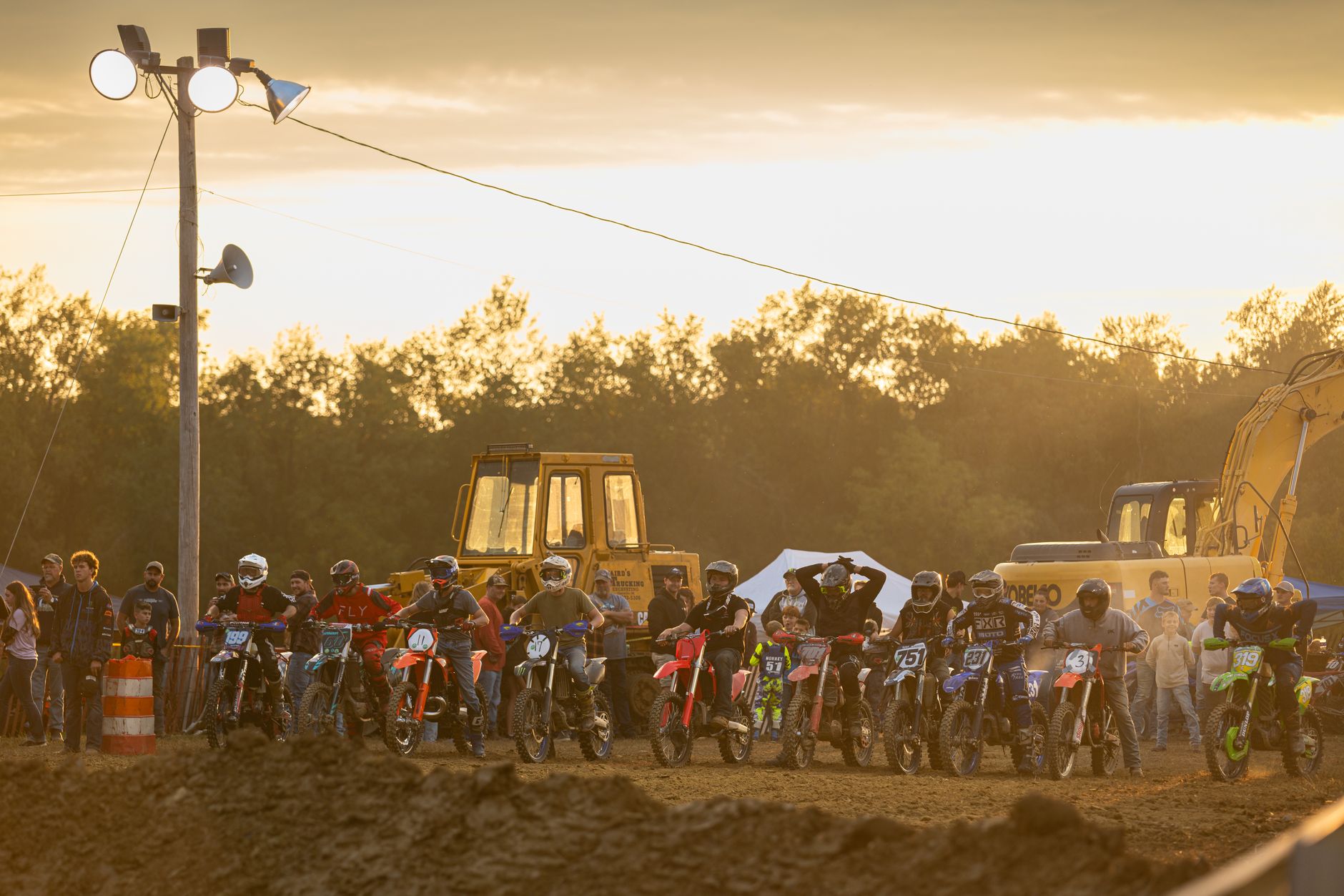 Exciting motocross event in West Alexander, PA at sunset with dirt bikes and lively crowd.