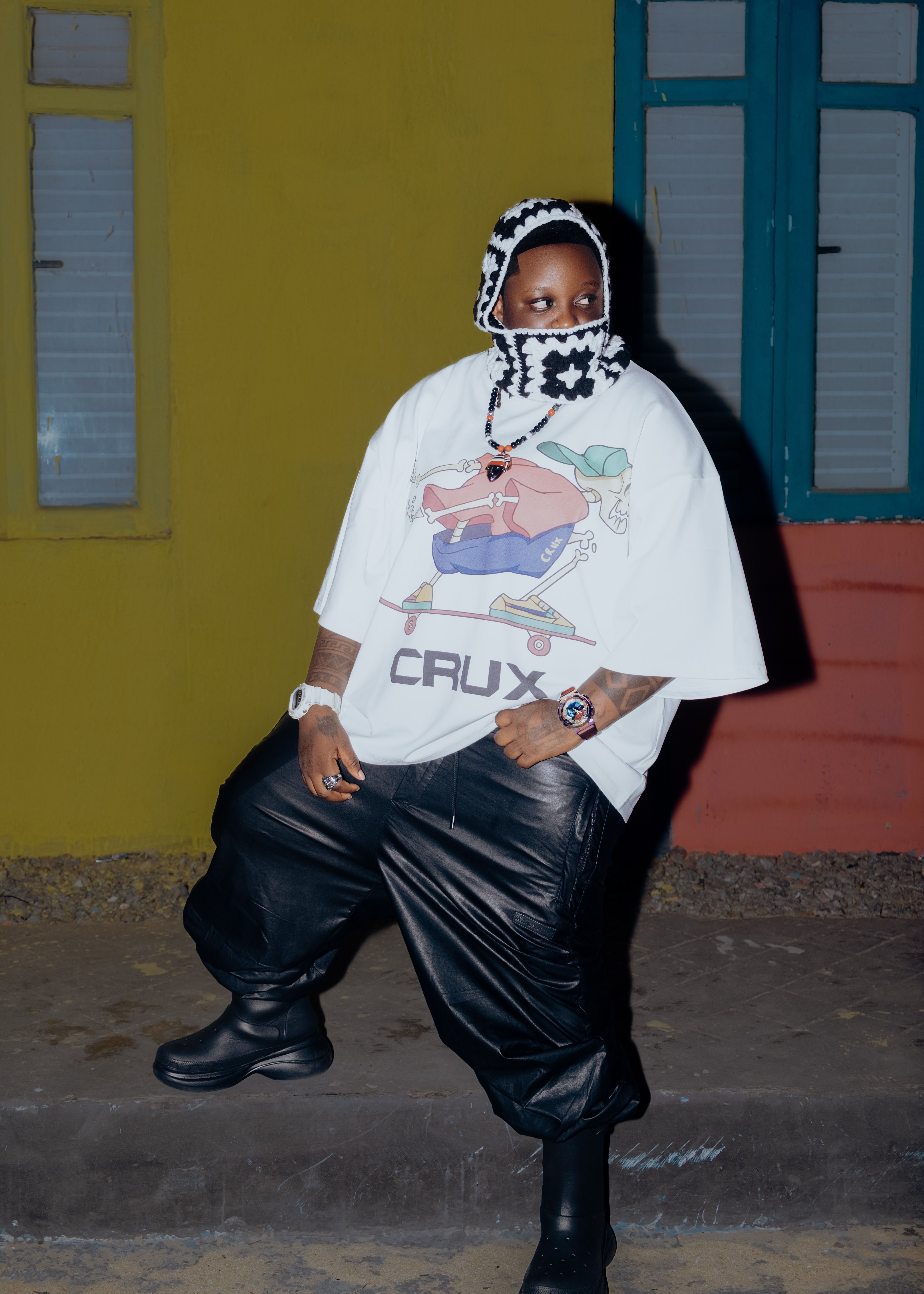 Casual urban fashion with graphic tee and leather pants, captured at night.