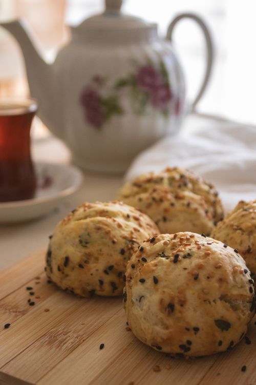 Free Freshly baked savory buns with sesame seeds, presented with a teapot and Turkish tea. Stock Photo