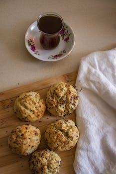 Warm baked rolls with seeds and a cup of tea on a wooden board.