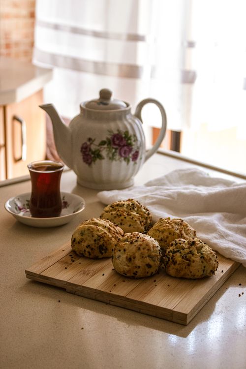 Free A serene indoor scene featuring a teapot, glass of tea, and freshly baked scones. Stock Photo