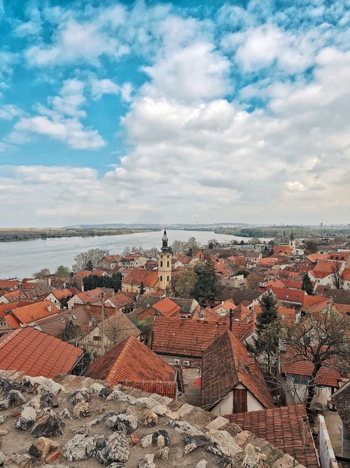 Free A stunning aerial view capturing the red-tiled rooftops and church tower in a historic European town by the river. Stock Photo