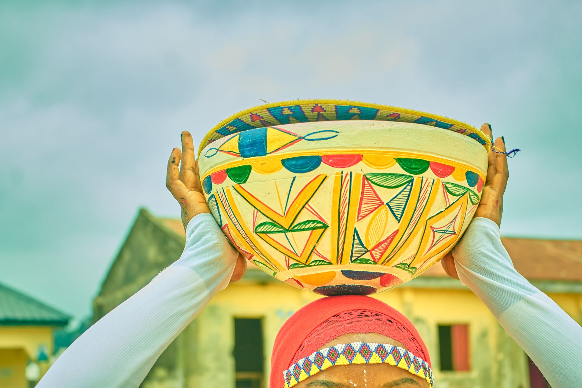 Vibrant African basket held over head, showcasing traditional art and culture.
