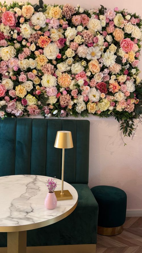 Free Chic cafe interior featuring a vibrant floral wall and elegant seating area. Stock Photo
