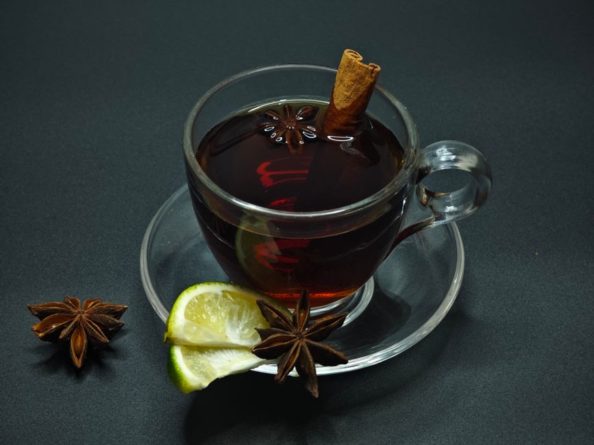 A warm cup of spiced tea garnished with lemon, star anise, and cinnamon stick.