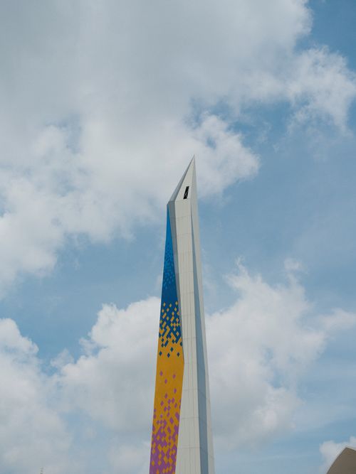 Free A vibrant, artistic tower standing tall against a bright, cloudy sky, showcasing modern Indonesian architecture. Stock Photo