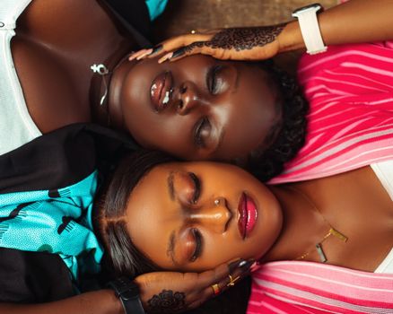 Close-up of two women with intricate henna art, lying symmetrically, showcasing diversity and beauty.