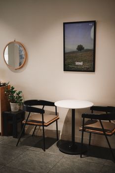 A cozy café corner featuring minimalist furniture, a round table, and wall art.